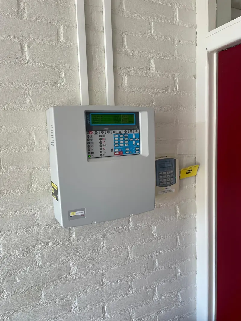 Brandmeldcentrale aan de wand, met het bedieningspaneel en de display