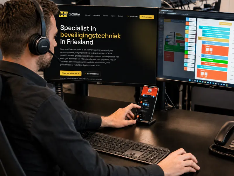 Medewerker belt via een VoIP-headset op een werkplek met meerdere schermen